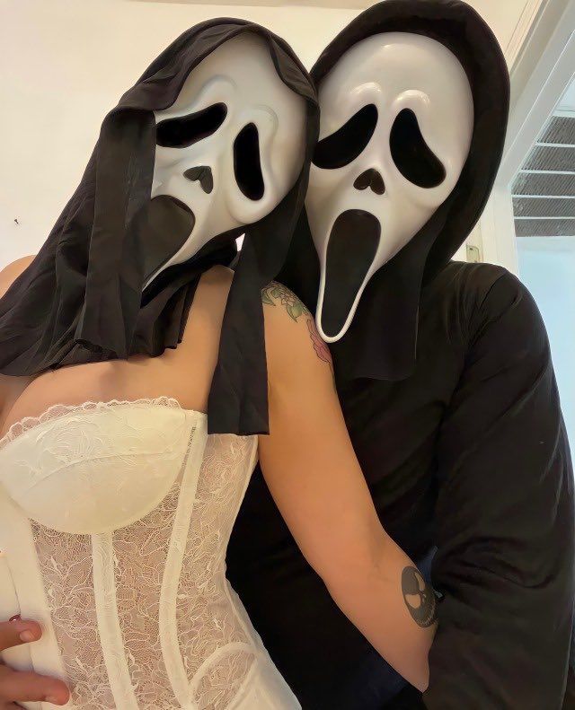 two people in masks hugging each other with their faces painted black and white, while the woman is wearing a corset