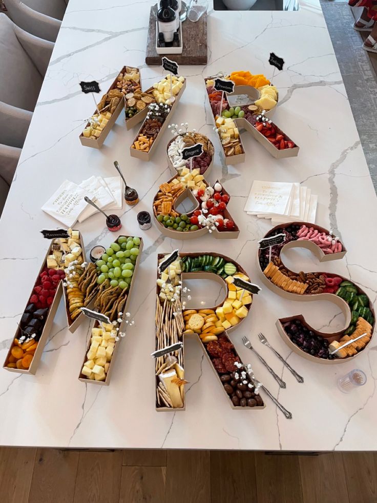 a table topped with lots of food on top of a white marble countertop covered in letters