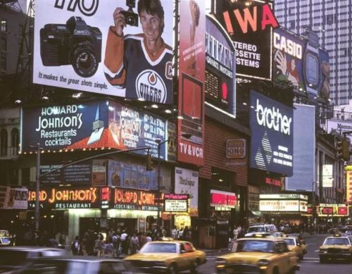 a busy city street filled with lots of traffic and tall buildings covered in billboards