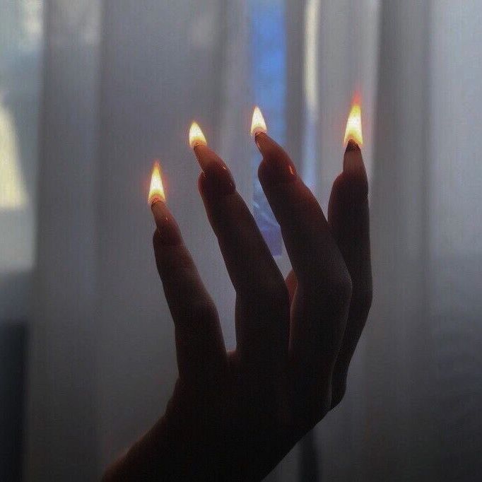 two hands holding lit matchsticks in front of a window