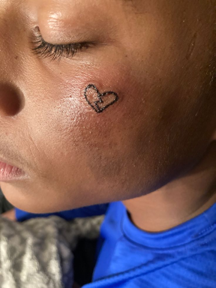 a child with a heart tattoo on his forehead