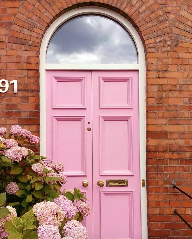 a pink door with flowers in front of it