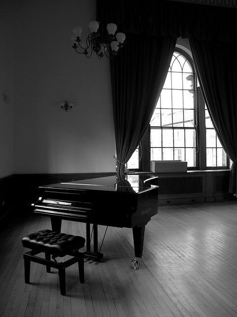 a piano sitting on top of a hard wood floor in front of a purple wall