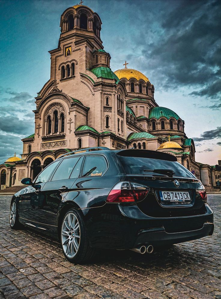 a black car parked in front of a building with domes on it's roof