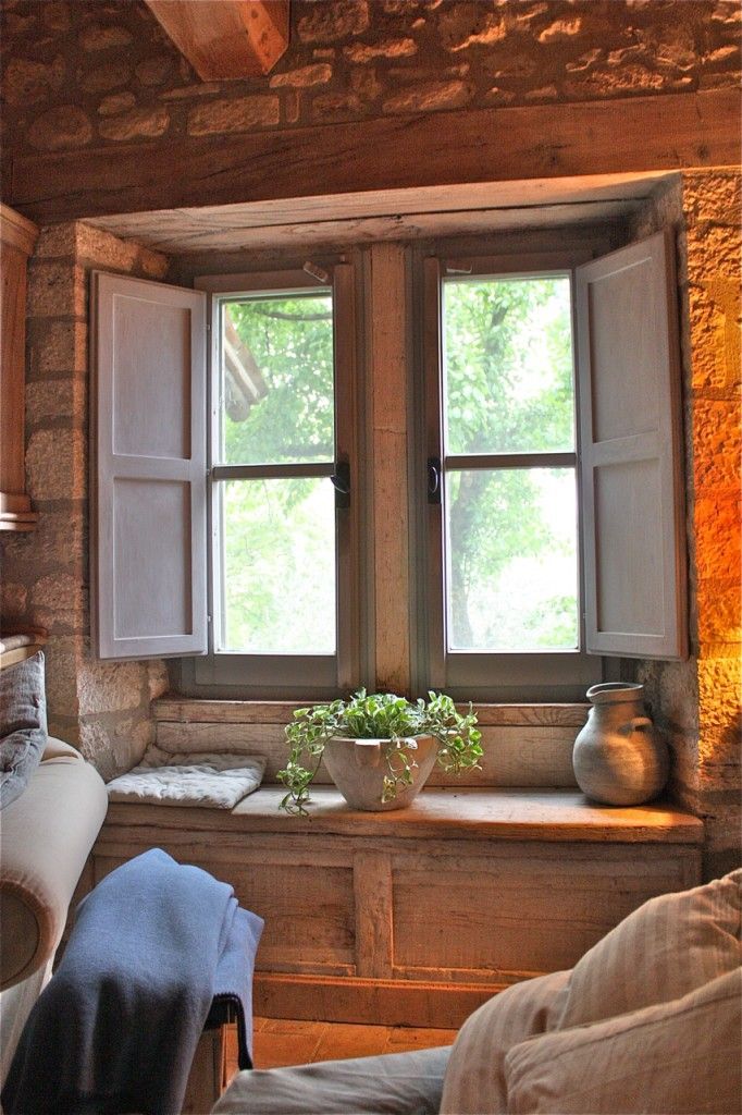 a window in a stone building with potted plants on the ledge and windowsill