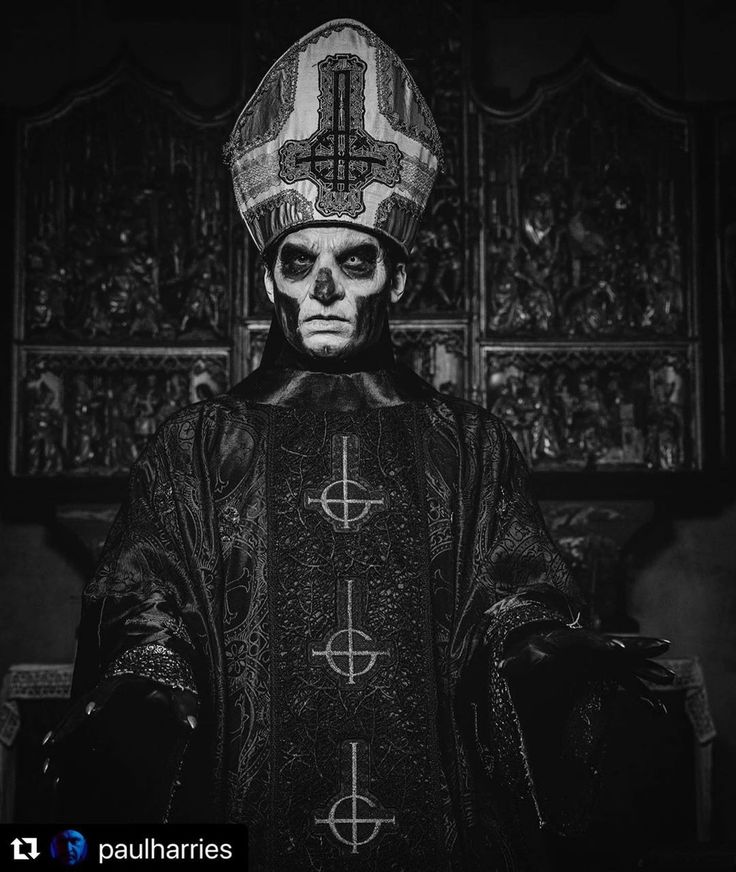 a black and white photo of a man in a priest's outfit with skulls on his face