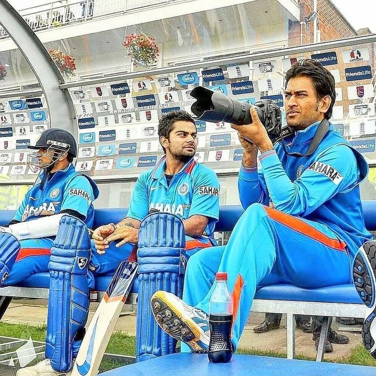 three men in blue cricket uniforms sitting on benches