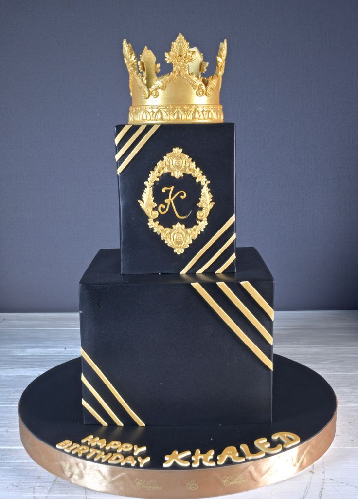 a three tiered black and gold cake with a crown on top