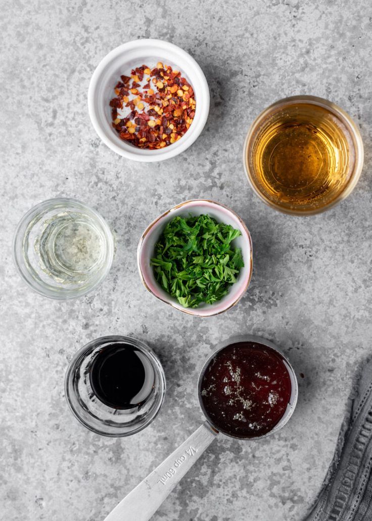 four bowls with different types of food in them next to a knife and some glasses