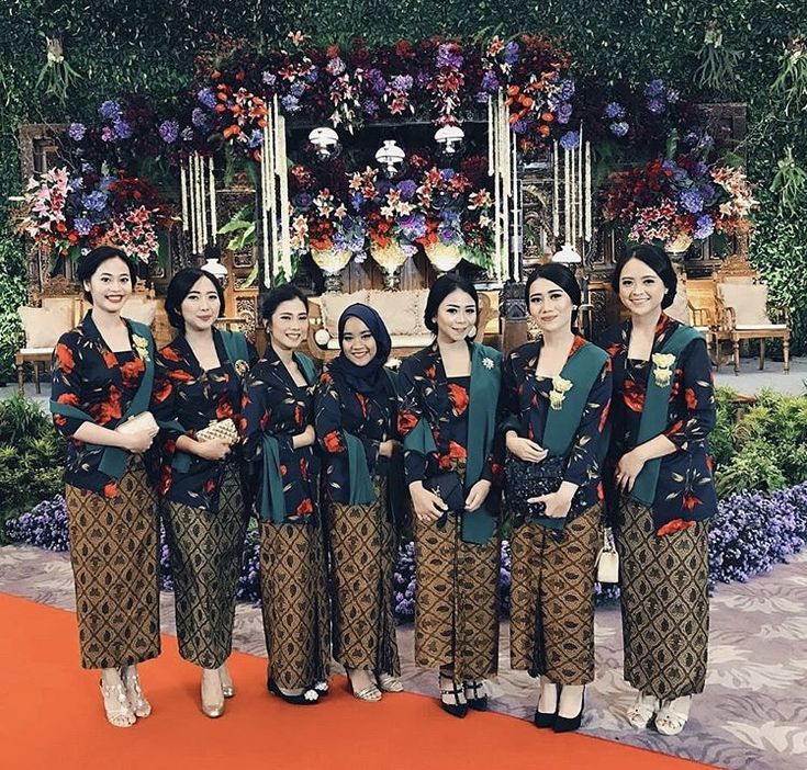 a group of women standing next to each other in front of a flower covered wall