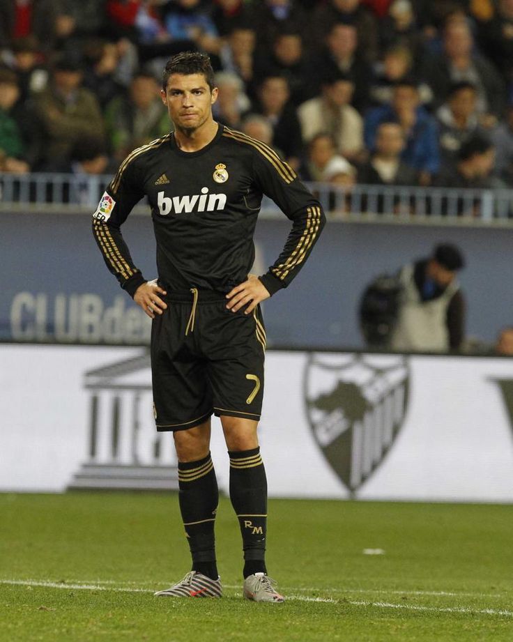 a soccer player is standing on the field with his hands on his hips and looking at the camera