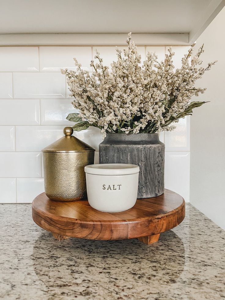 a vase with some flowers in it sitting on a counter top next to a salt and pepper shaker