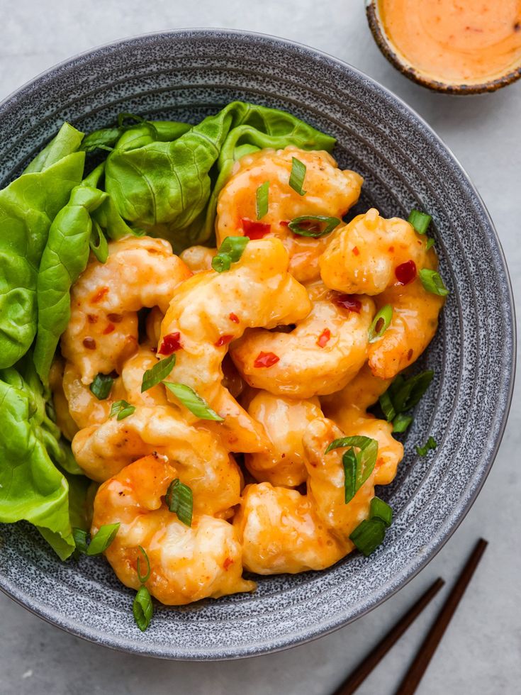 a bowl filled with shrimp and lettuce next to chopsticks