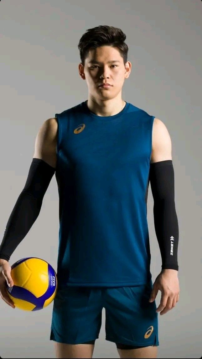 a man holding a yellow and blue soccer ball in his right hand while wearing a sleeveless shirt