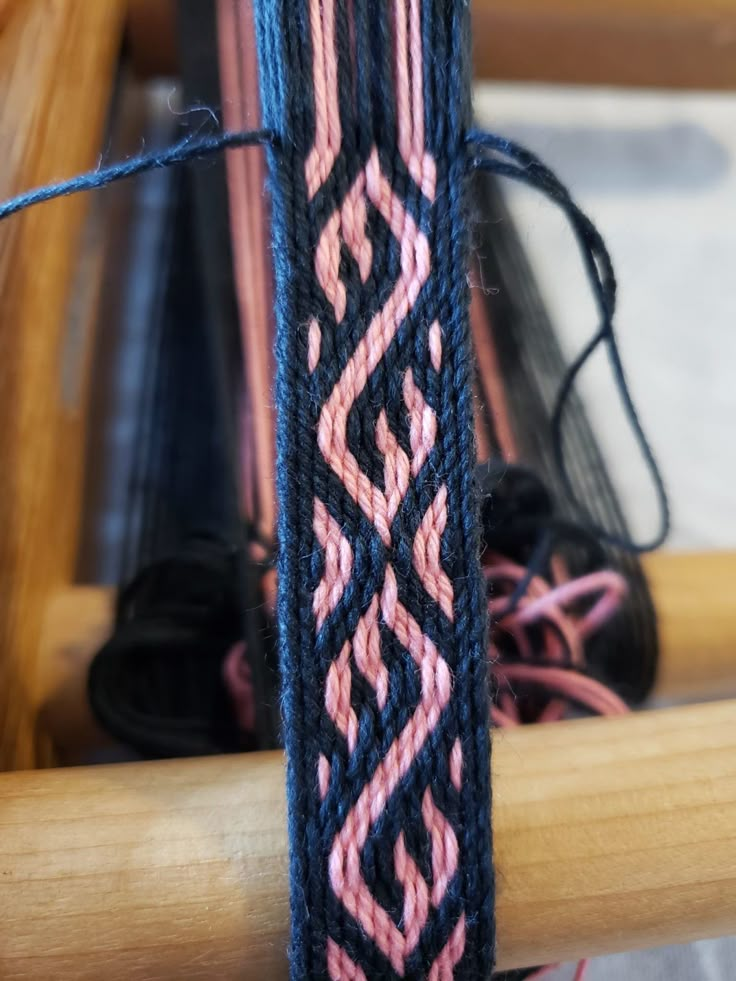 a close up view of the end of a weaving machine with pink and black designs on it