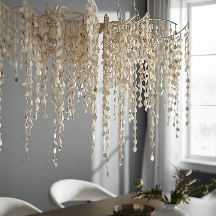 a chandelier hanging from the ceiling over a dining room table with white chairs