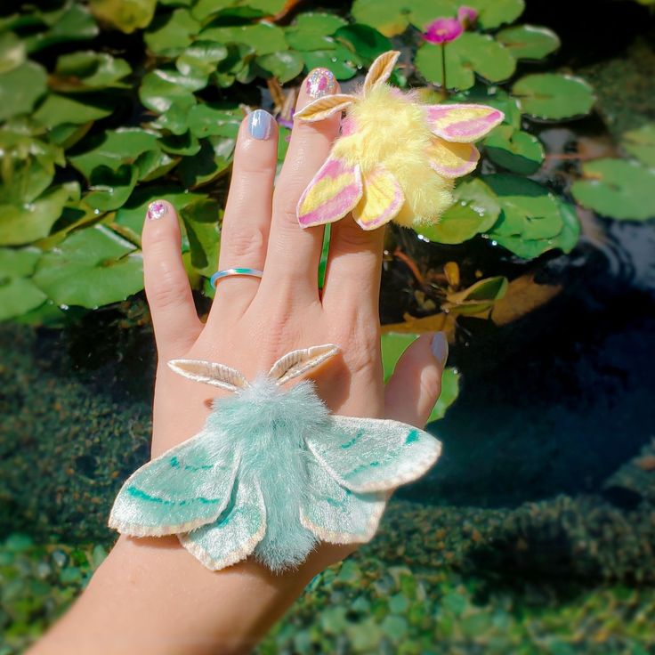 a woman's hand with a green and white butterfly ring on top of it