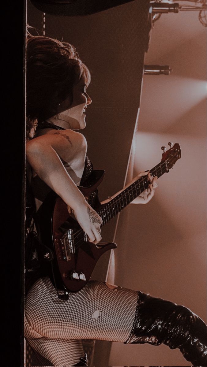 a woman in fishnet stockings and boots playing guitar