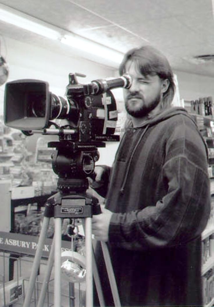 a man standing next to a camera on top of a tripod in a store