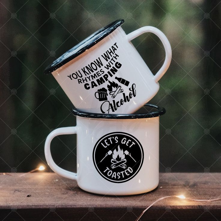 two white coffee mugs sitting on top of a wooden table next to each other