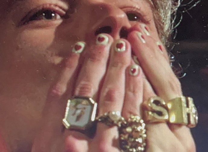 a close up of a person covering their face with her hands and wearing gold rings