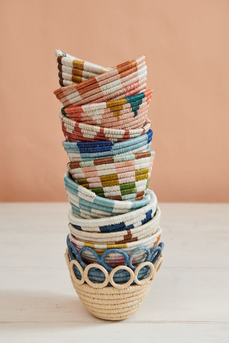 a stack of woven bracelets sitting on top of a white table next to a pink wall