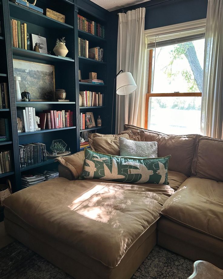 a living room filled with furniture and bookshelves next to a large open window