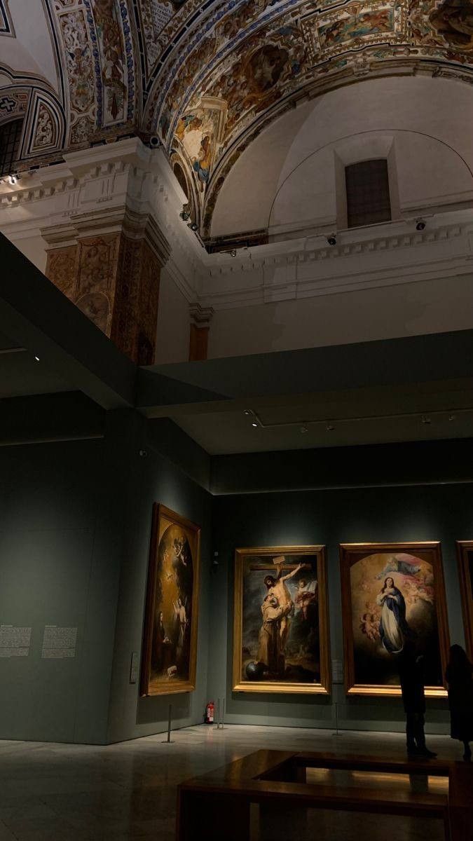 people looking at paintings on display in an art gallery with vaulted ceiling and painted ceilings