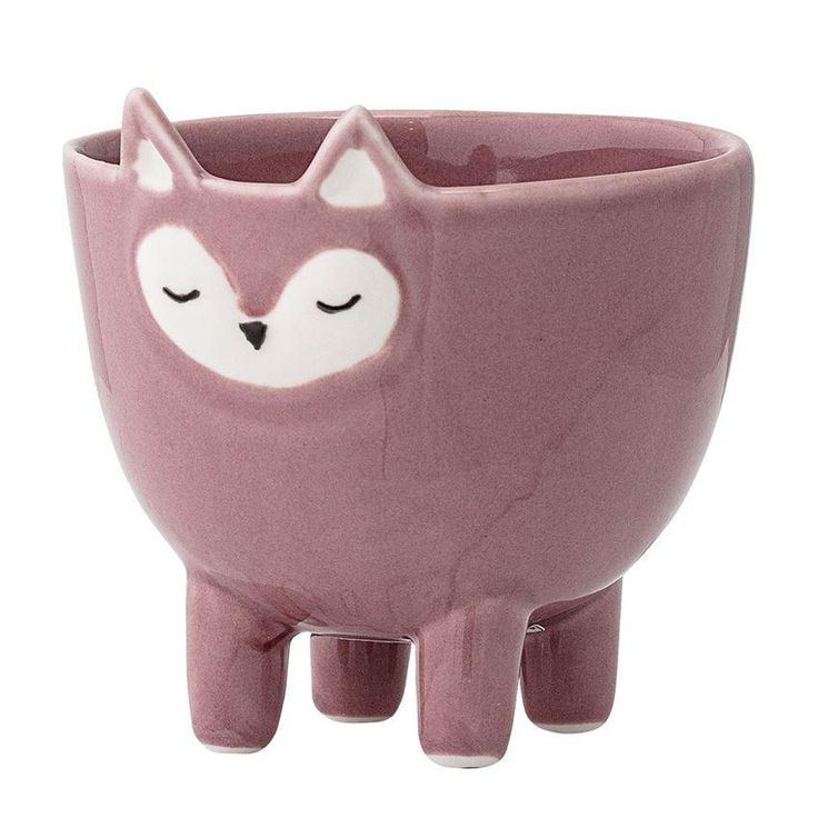 a pink ceramic cup with a white fox face on the side and eyes closed, sitting in front of a white background