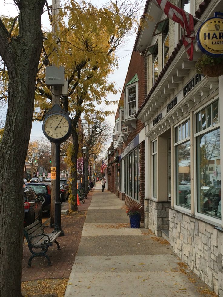 a clock on the side of a building next to a tree with leaves around it