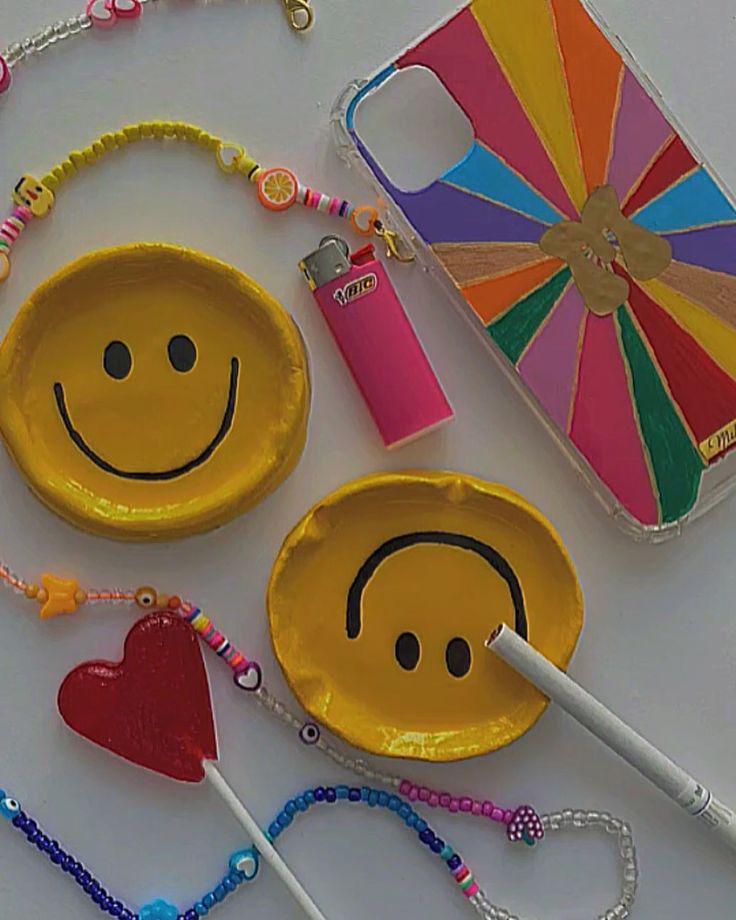 two yellow plates with smiley faces on them next to candy sticks and a phone case