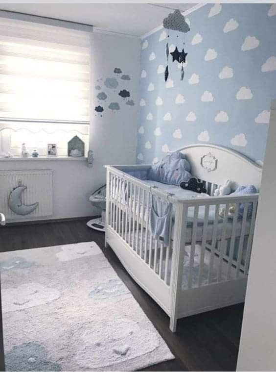 a baby's room with blue walls and clouds painted on the wall, along with a white crib