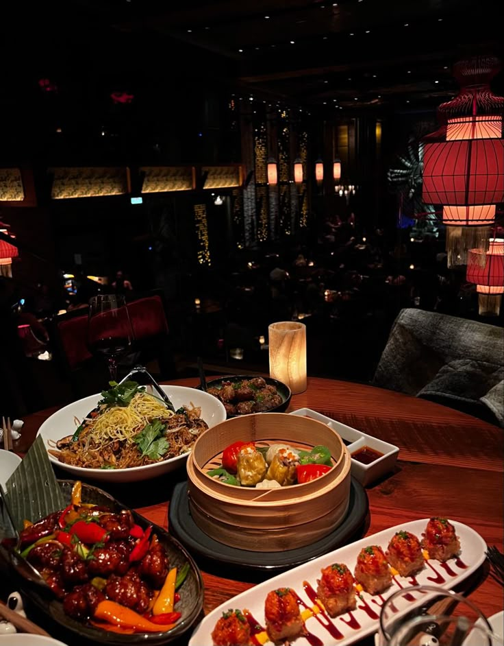 a wooden table topped with lots of plates and bowls filled with different types of food