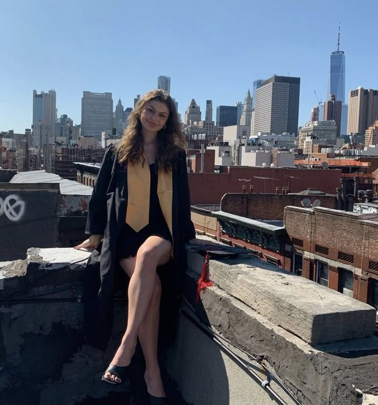 a woman sitting on top of a roof next to a tall cityscape with buildings in the background