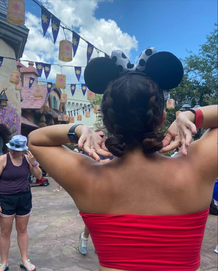 the back of a woman's head in front of mickey mouse ears at disneyland