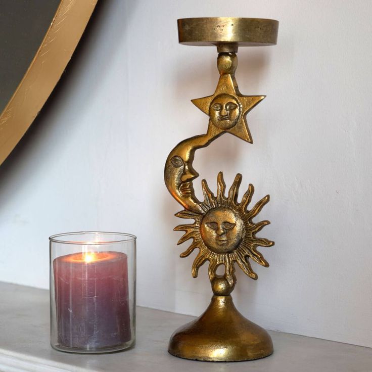 a candle holder with a sun and moon design on it next to a lit candle