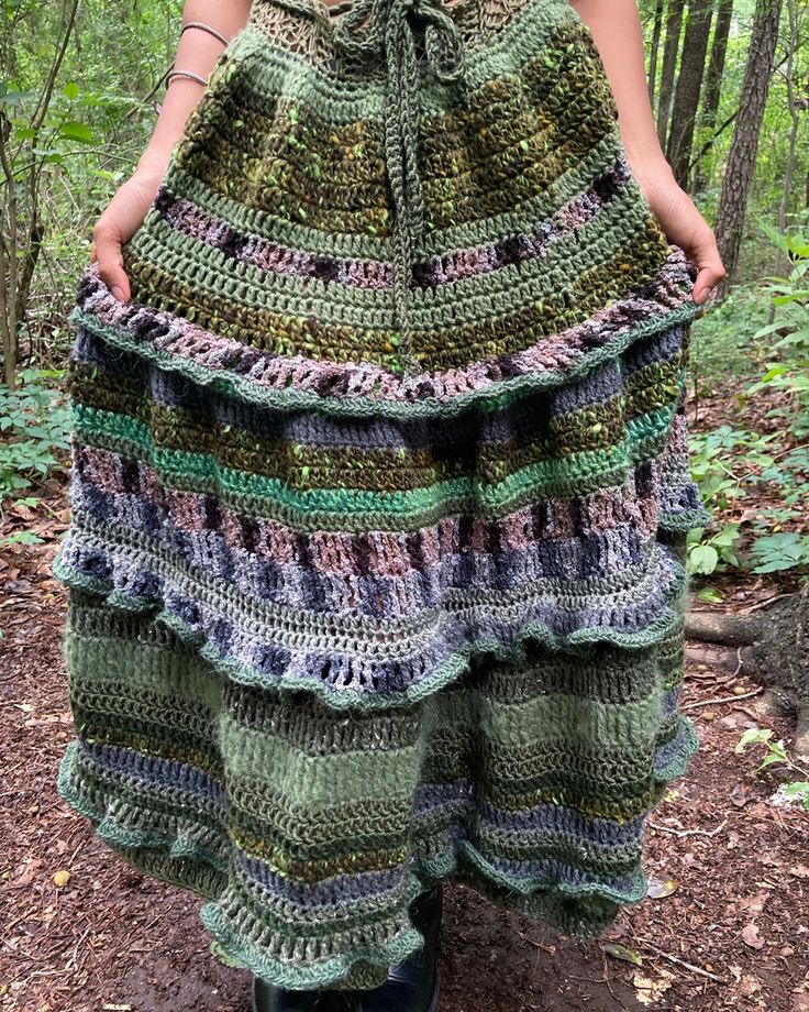 a woman is standing in the woods wearing a crocheted skirt with ruffles