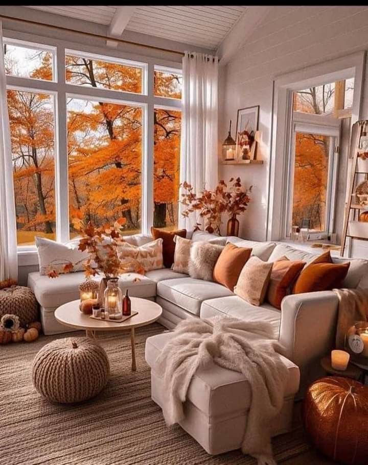 a living room filled with lots of furniture next to large windows covered in fall foliage