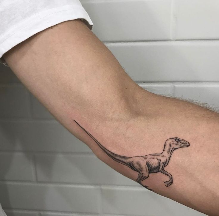 a small dinosaur tattoo on the arm