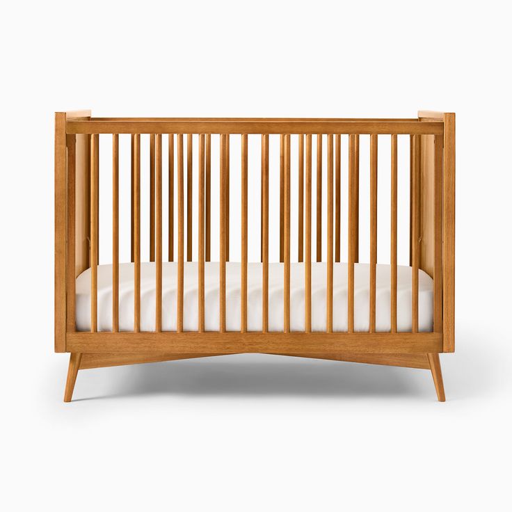 a wooden crib with white sheets on the bottom and sides, against a white background