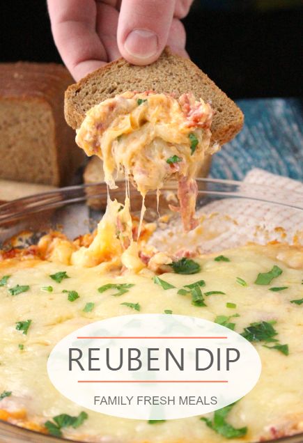 a person holding a piece of bread over a casserole dish with cheese and vegetables