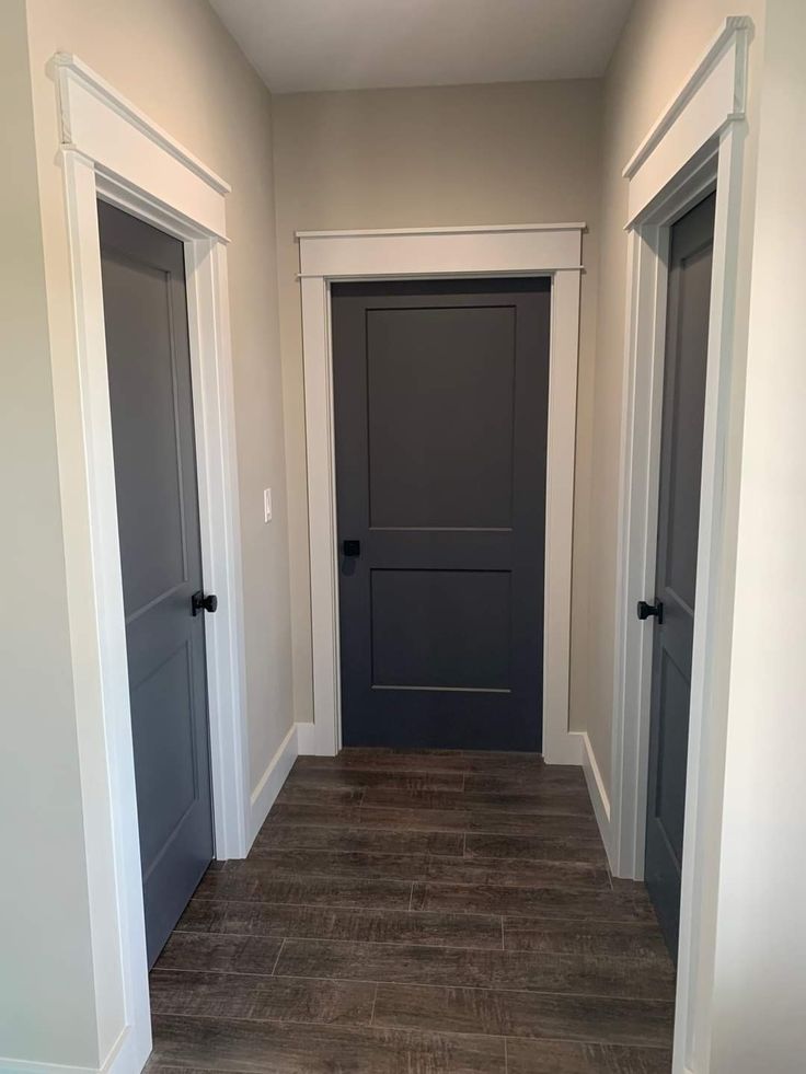 an empty hallway with two doors and wood flooring on either side of the door