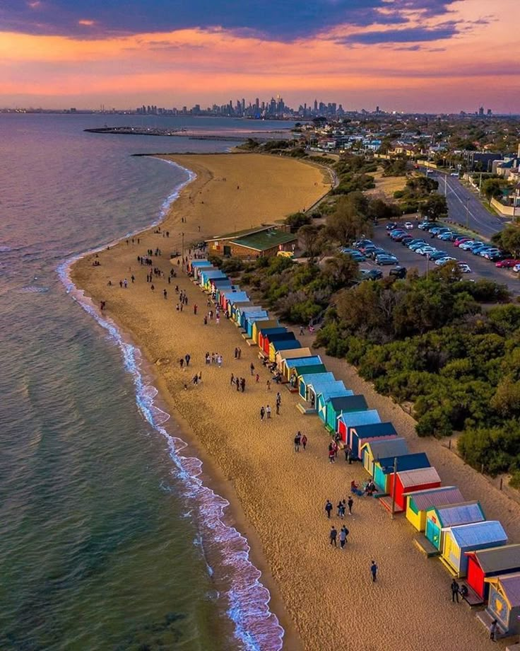 an aerial view of the beach with many colorful cabanas and people walking on it