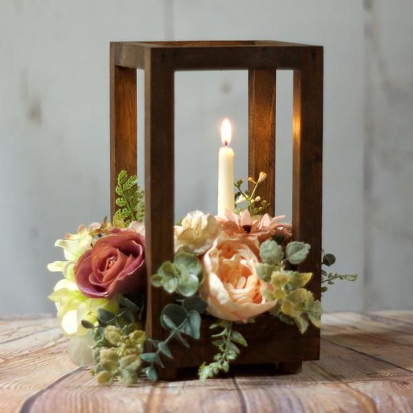 a candle holder with flowers and greenery in it