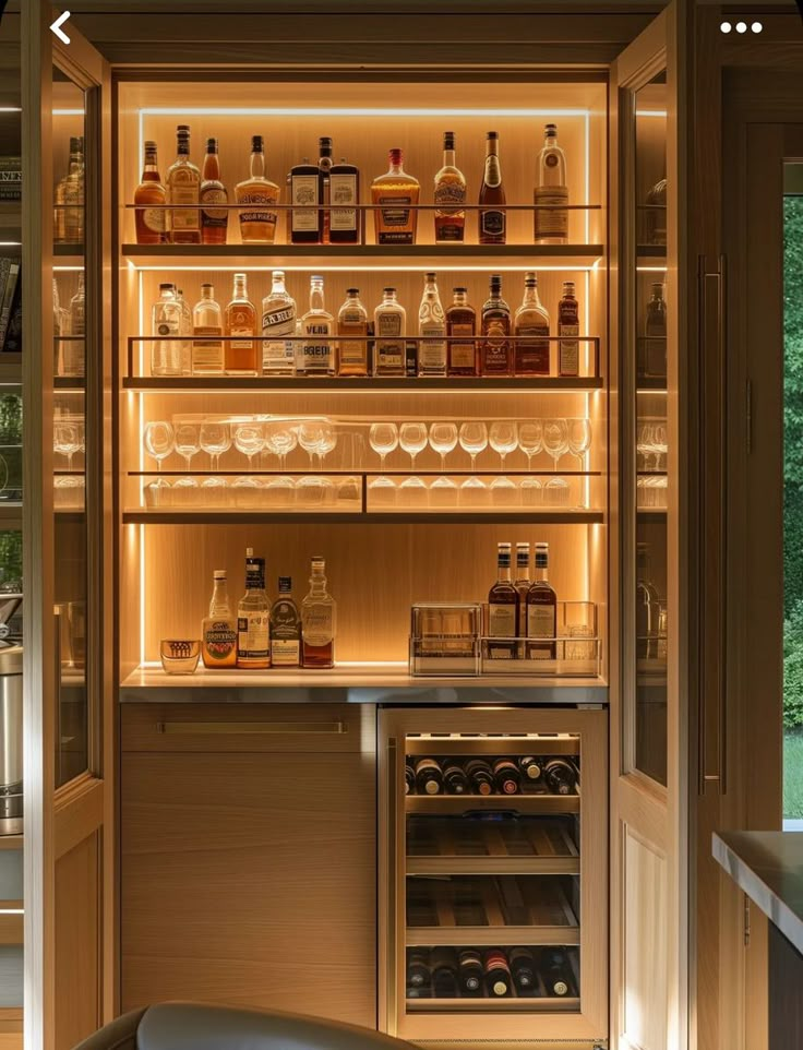 an open refrigerator filled with lots of bottles and glasses on it's shelves next to a window