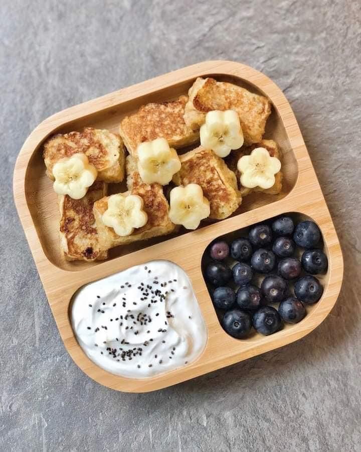 a wooden tray with blueberries, bananas and yogurt in it on a table