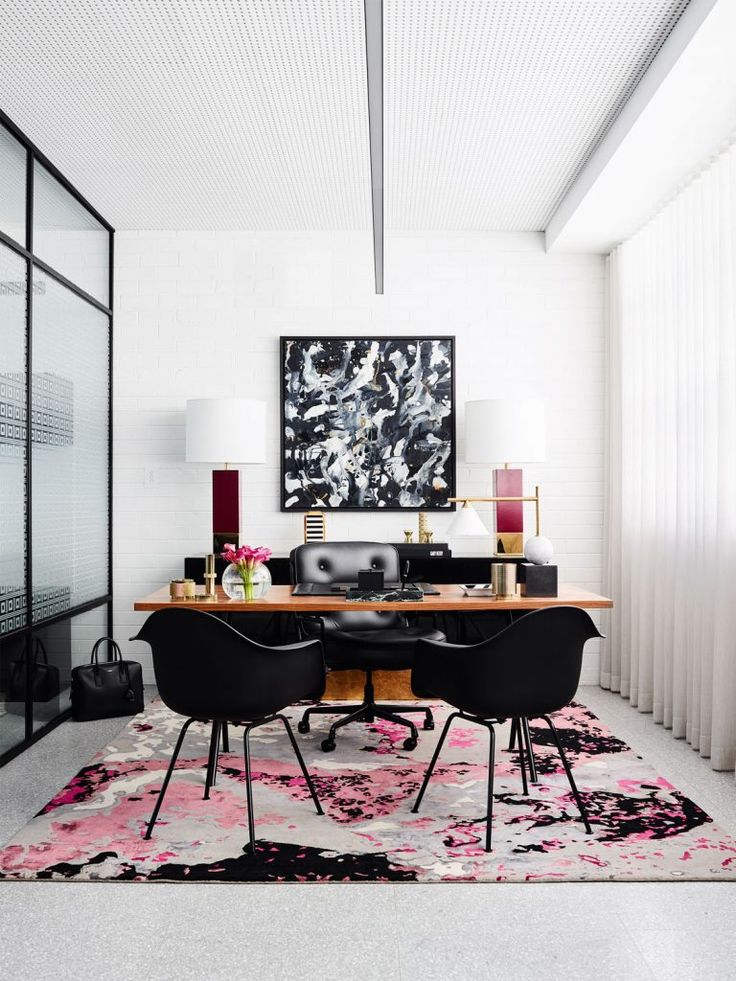 an office with black chairs and a pink rug on the floor in front of a large painting