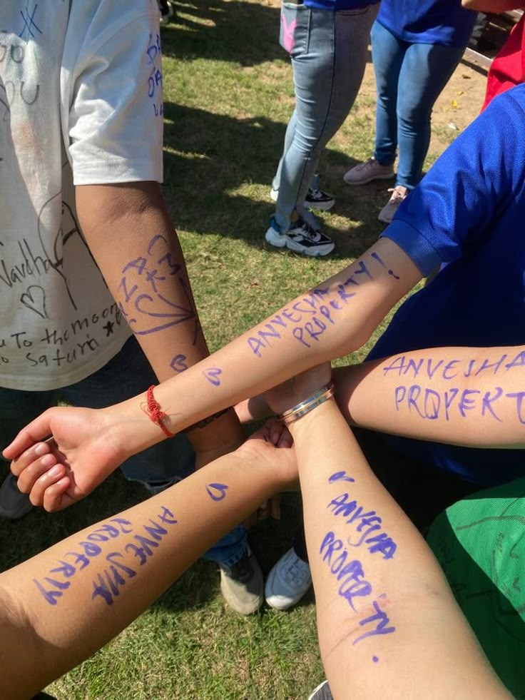 several people are holding hands with writing on their arms in the middle of a circle