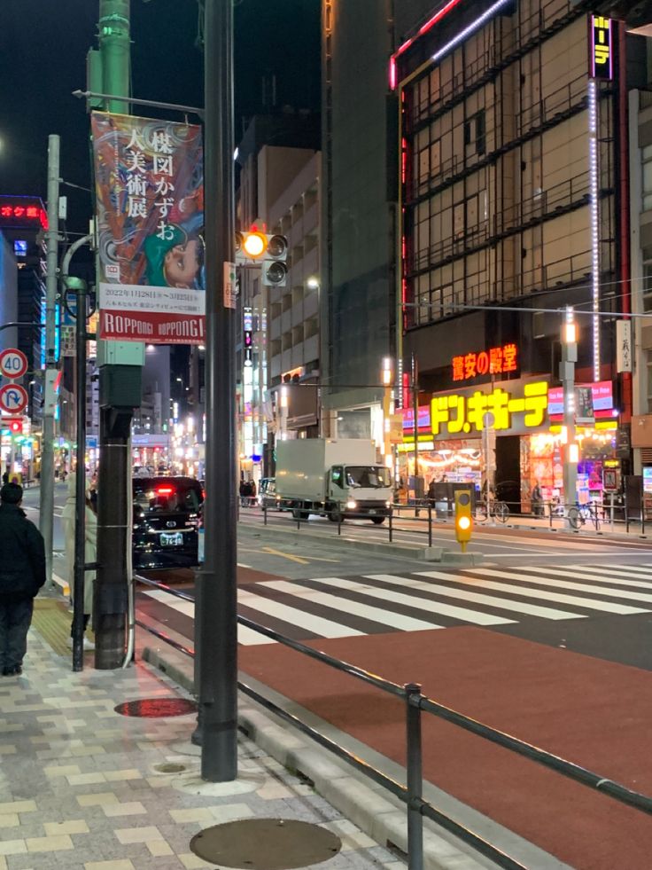 a city street at night with people walking on the sidewalk