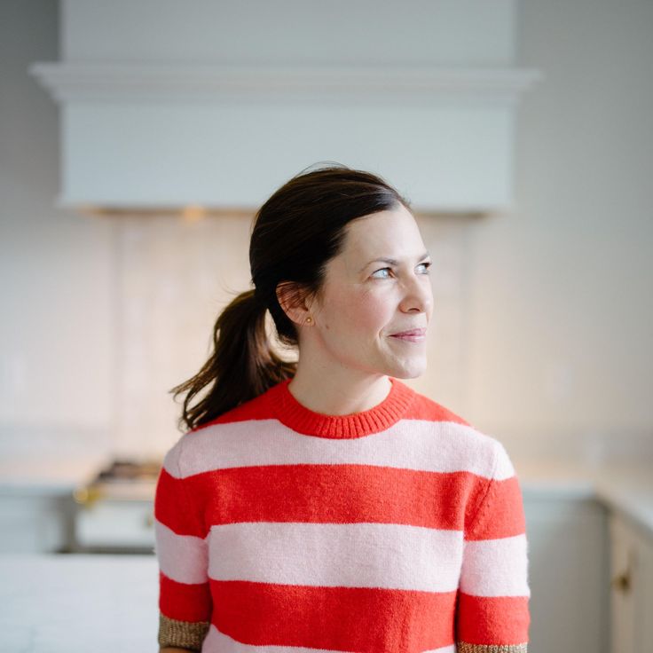 a woman in a red and white striped sweater is standing in a kitchen looking off to the side